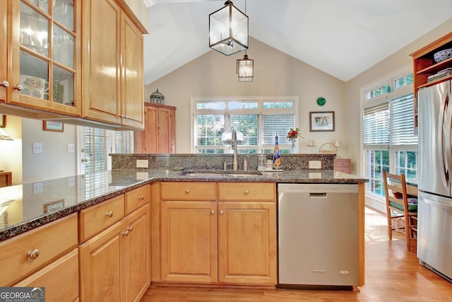 kitchen featuring light brown cabinets, a sink, light wood-style floors, appliances with stainless steel finishes, and dark stone counters