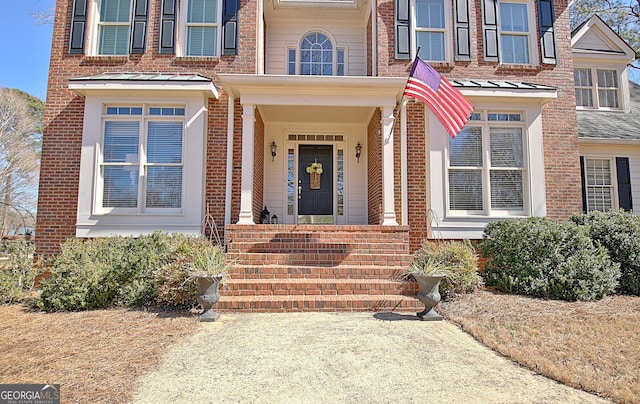 view of exterior entry featuring a standing seam roof, brick siding, and metal roof