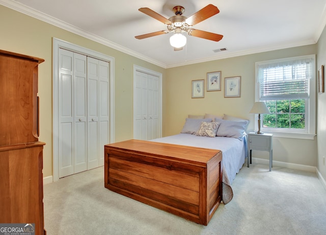 bedroom featuring light carpet, crown molding, visible vents, and multiple closets