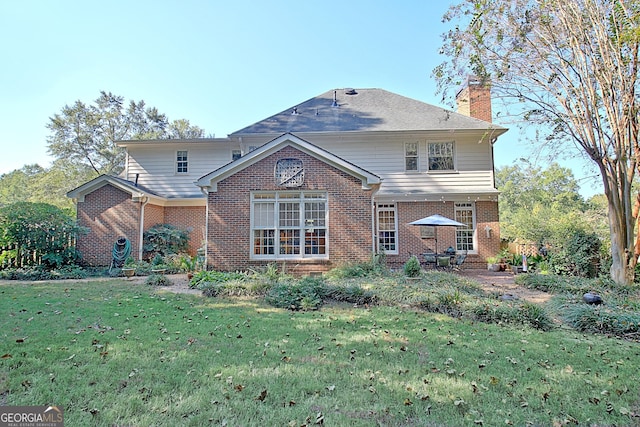 rear view of property featuring a yard, a chimney, and brick siding