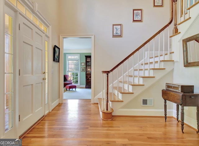 entrance foyer featuring baseboards, stairs, visible vents, and wood finished floors