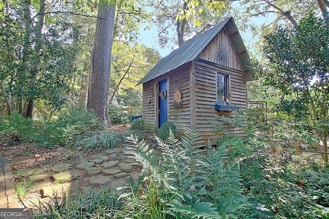 view of side of home with an outbuilding, metal roof, and a shed