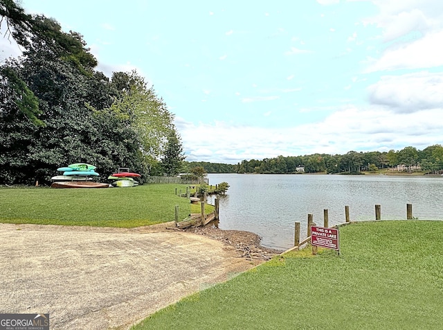 view of dock with a water view and a lawn