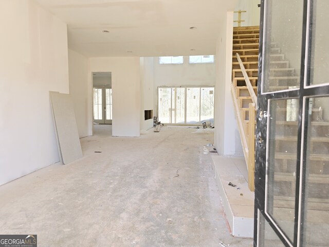 unfurnished living room featuring stairs and french doors