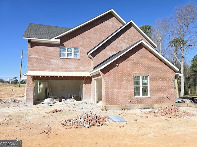 exterior space featuring an attached garage, roof with shingles, and brick siding