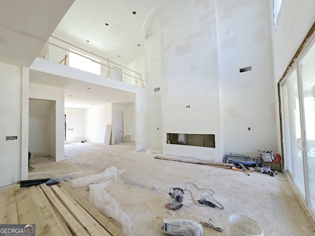 unfurnished living room featuring a towering ceiling and a fireplace