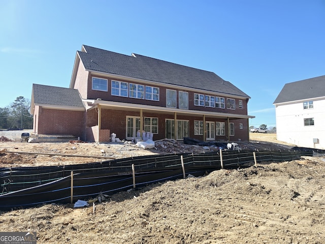 rear view of house featuring brick siding and fence