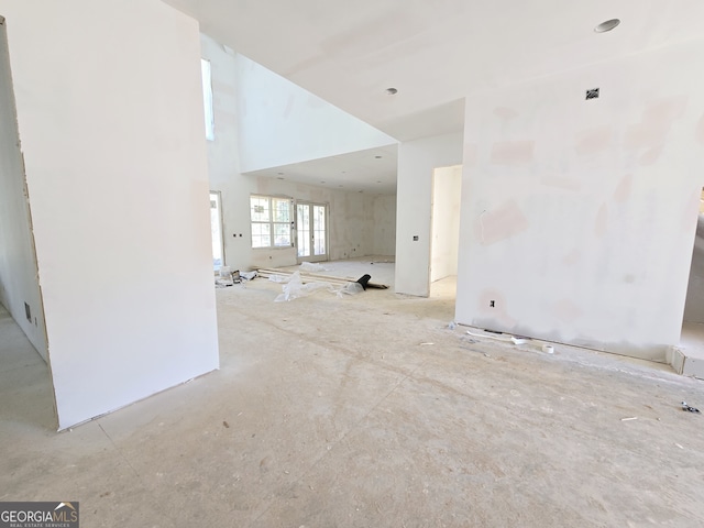 unfurnished living room featuring a towering ceiling