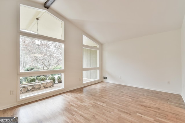 spare room with vaulted ceiling, light wood-style floors, visible vents, and baseboards