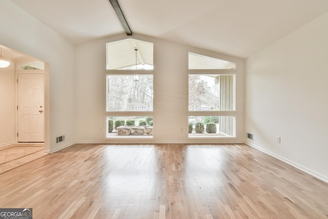 unfurnished living room featuring baseboards, beam ceiling, and light wood-style flooring