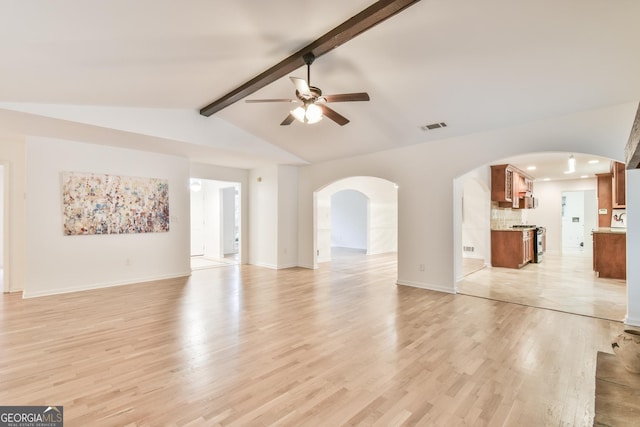 unfurnished living room featuring visible vents, a ceiling fan, lofted ceiling with beams, arched walkways, and light wood-style floors