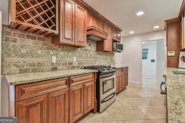 kitchen featuring light stone countertops, backsplash, appliances with stainless steel finishes, and brown cabinets