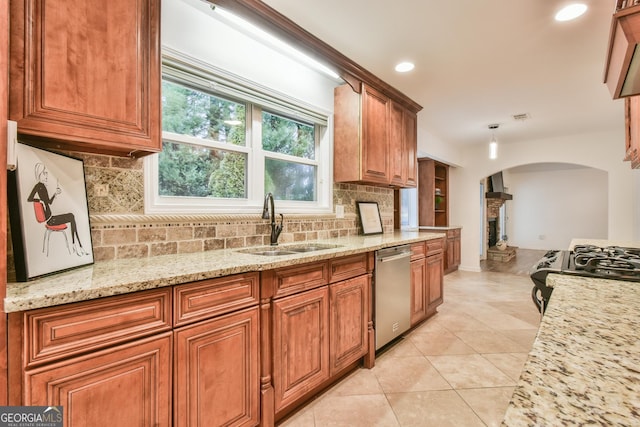 kitchen featuring a sink, black gas range oven, brown cabinetry, light tile patterned floors, and dishwasher