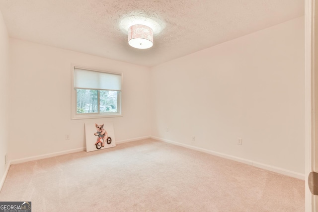 unfurnished room featuring baseboards, light colored carpet, and a textured ceiling