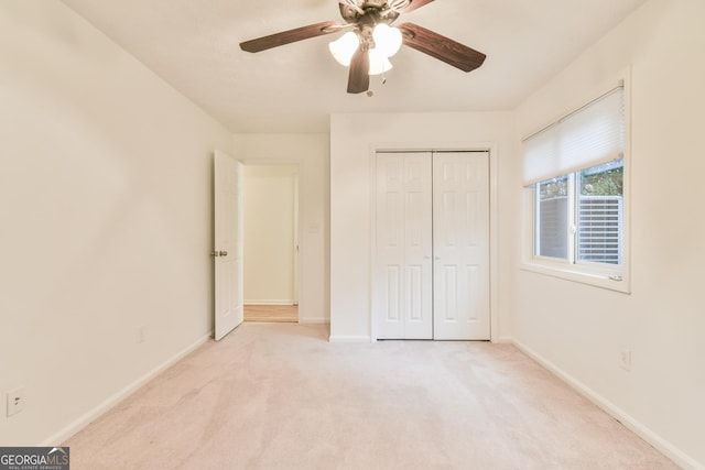 unfurnished bedroom featuring a closet, baseboards, light colored carpet, and ceiling fan