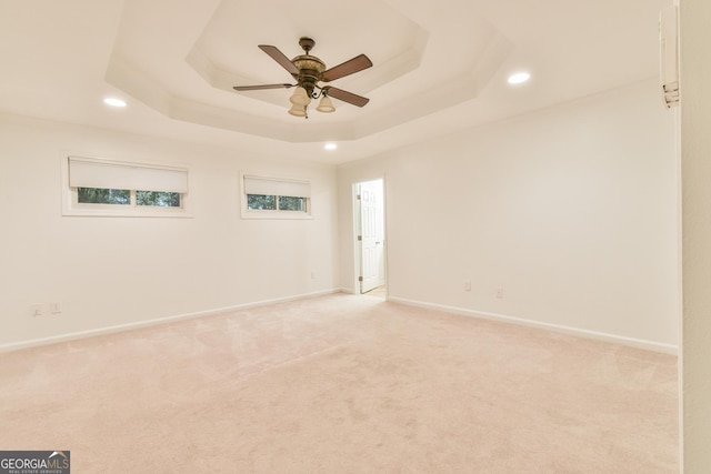 unfurnished room with recessed lighting, a tray ceiling, baseboards, and light carpet