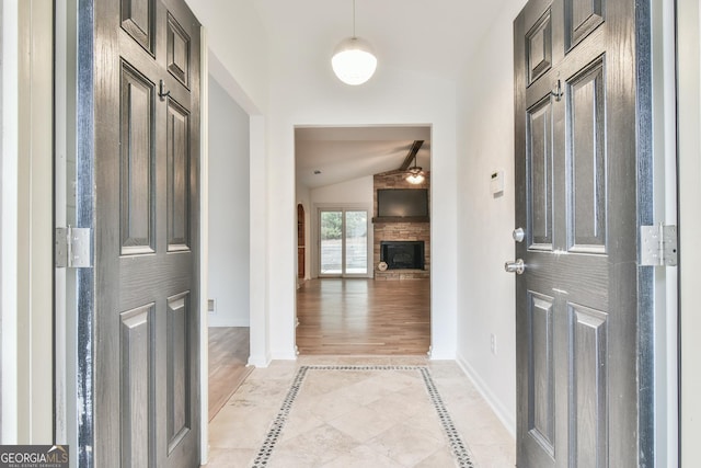 entrance foyer with lofted ceiling, light wood-style flooring, baseboards, and a large fireplace