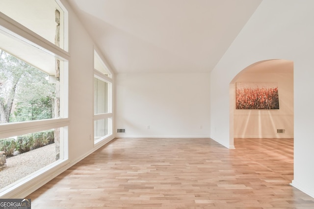 spare room with light wood finished floors, visible vents, arched walkways, and baseboards