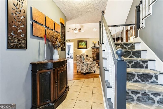 stairs with tile patterned flooring, vaulted ceiling, ceiling fan, and a textured ceiling