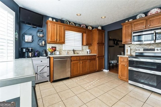 kitchen featuring brown cabinets, stainless steel appliances, light countertops, and light tile patterned flooring