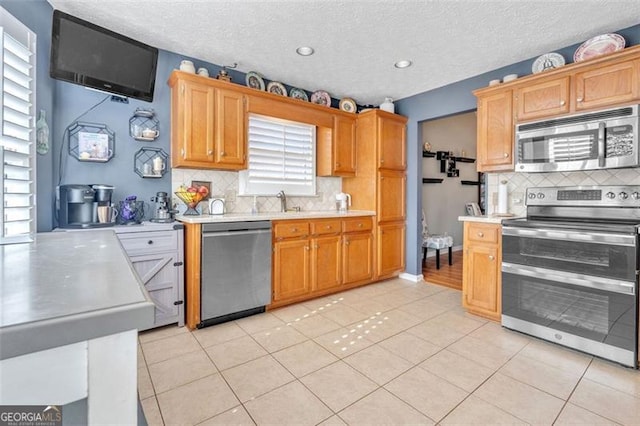 kitchen with stainless steel appliances, light countertops, backsplash, and light tile patterned floors