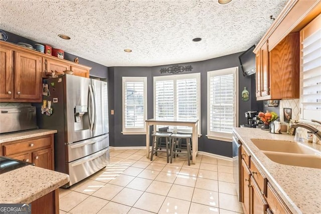 kitchen with a sink, tasteful backsplash, brown cabinetry, and stainless steel fridge