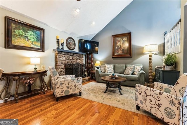 sitting room with a fireplace, vaulted ceiling, and wood finished floors