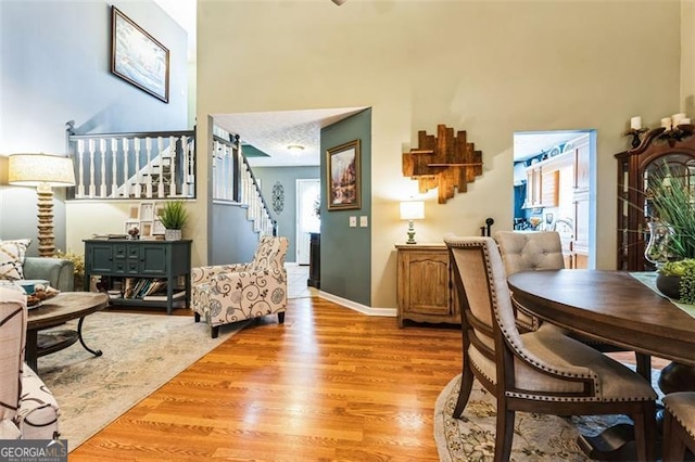 interior space featuring a high ceiling, baseboards, stairway, and light wood finished floors