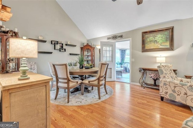 dining room featuring light wood-type flooring, high vaulted ceiling, and a ceiling fan