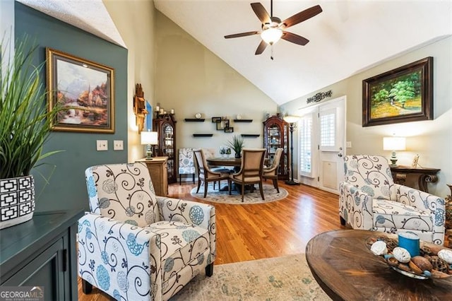 living area featuring vaulted ceiling, light wood-style flooring, and a ceiling fan