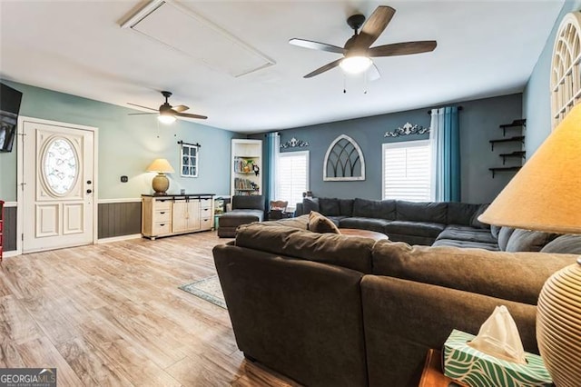 living area featuring attic access, a ceiling fan, and wood finished floors