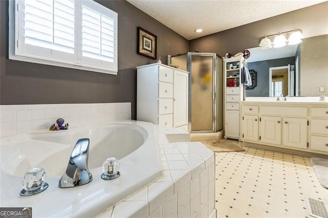 full bathroom featuring a garden tub, a stall shower, vanity, a textured ceiling, and tile patterned floors