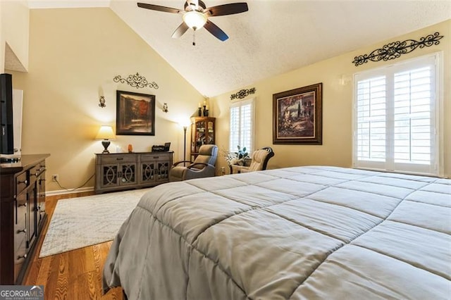 bedroom with baseboards, ceiling fan, wood finished floors, a textured ceiling, and high vaulted ceiling