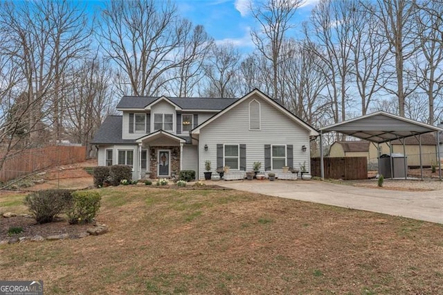 traditional-style home featuring an outbuilding, fence, concrete driveway, a detached carport, and a front yard