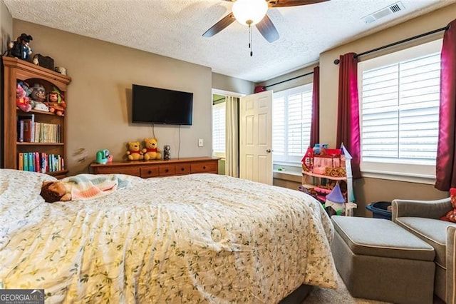 bedroom featuring a ceiling fan, visible vents, and a textured ceiling