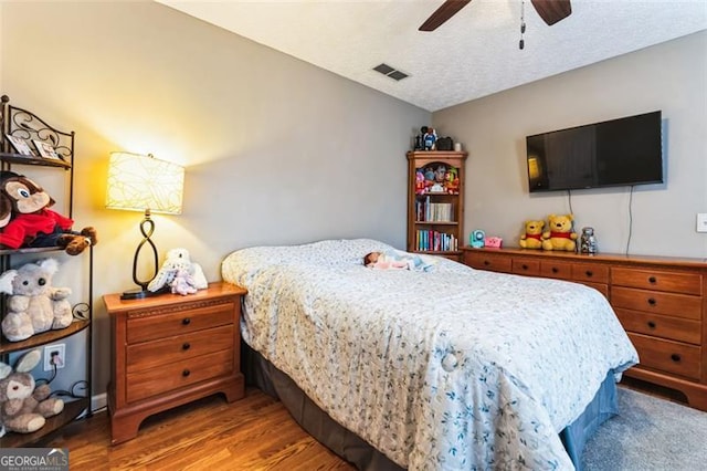 bedroom featuring visible vents, ceiling fan, a textured ceiling, and wood finished floors