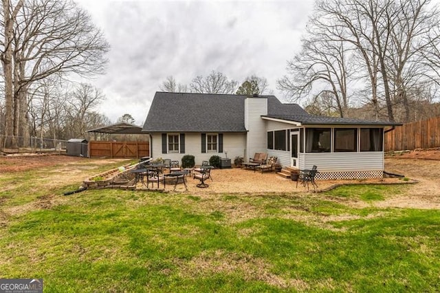 back of property featuring an outdoor fire pit, a sunroom, a yard, and fence