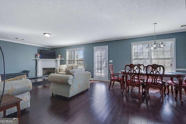 living room with a notable chandelier, a fireplace, ornamental molding, a textured ceiling, and hardwood / wood-style flooring