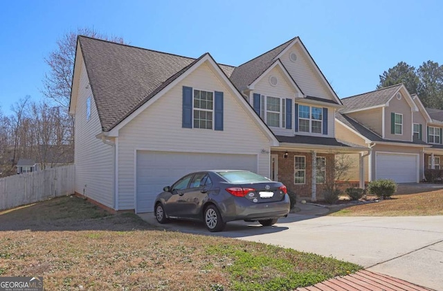 traditional-style home with concrete driveway, an attached garage, and fence