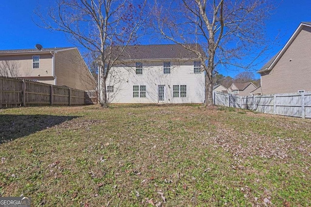 rear view of property with a fenced backyard and a yard