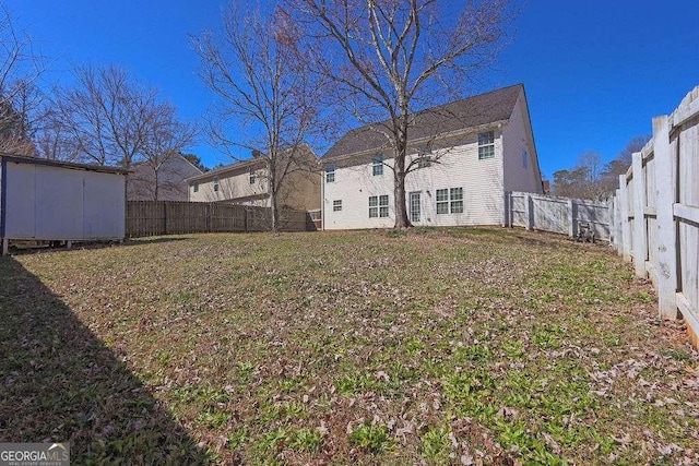 view of yard with a fenced backyard, an outdoor structure, and a storage unit