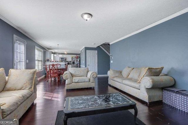 living area featuring baseboards, crown molding, hardwood / wood-style floors, and an inviting chandelier