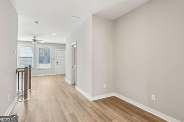 corridor featuring visible vents, baseboards, light wood finished floors, and an upstairs landing