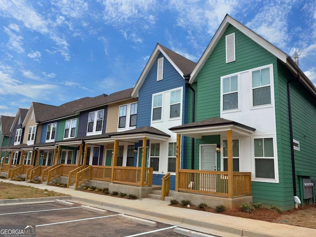 townhome / multi-family property featuring uncovered parking, a residential view, and a porch