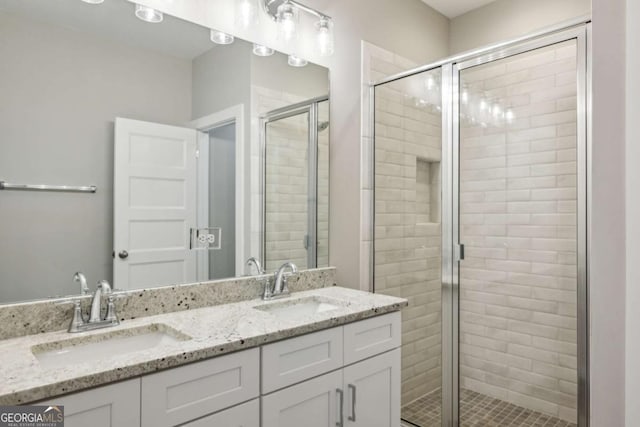 full bathroom with double vanity, a shower stall, and a sink