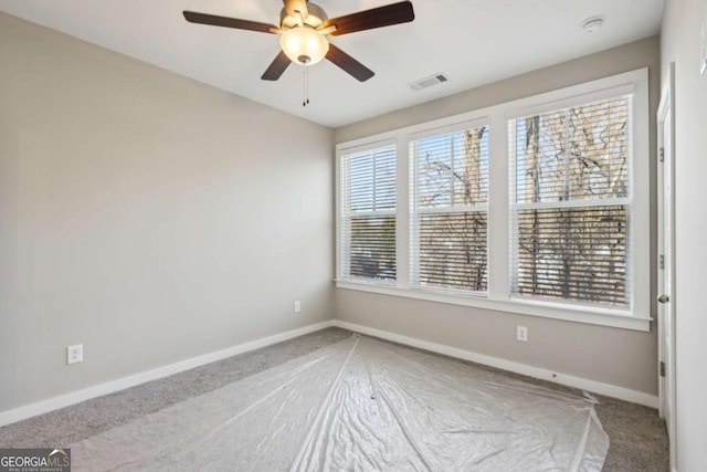 carpeted empty room featuring visible vents, baseboards, and ceiling fan