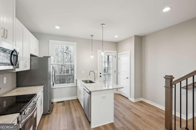 kitchen featuring a peninsula, light wood-style flooring, stainless steel appliances, and a sink