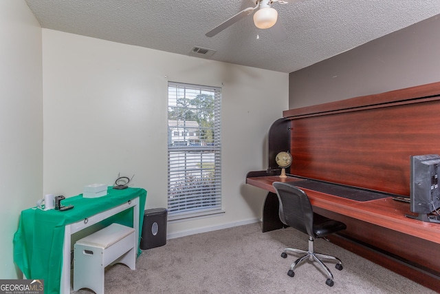 carpeted office with a textured ceiling, ceiling fan, visible vents, and baseboards