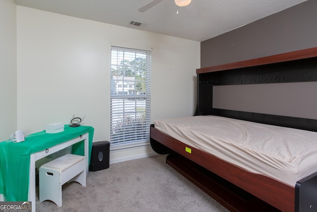 carpeted bedroom with ceiling fan, visible vents, and a textured ceiling