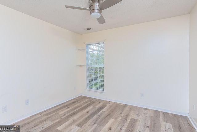 empty room with a ceiling fan, wood finished floors, visible vents, and baseboards